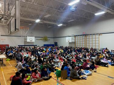Students and families gathered in the school gym on the floor, ready to watch a movie