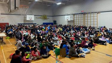 Harry Sayers - March Movie Night Students and families gathered in the school gym on the floor, ready to watch a movie