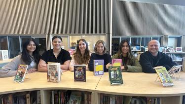 Six smiling teacher candidates standing in the library